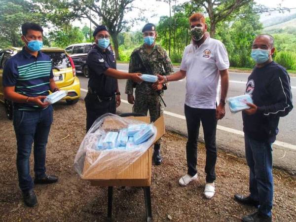 Jasvir Singh (dua dari kanan) menyerahkan sumbangan pelitup muka kepada petugas di sekatan jalan raya Benus dan sekatan jalan raya Jalan Lama Kuala Lumpur-Bentong.